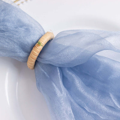 Blue sheer napkin tied with a natural woven ring on a white plate.