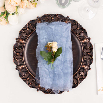 Elegant blue napkin with floral accent on ornate plate setting.