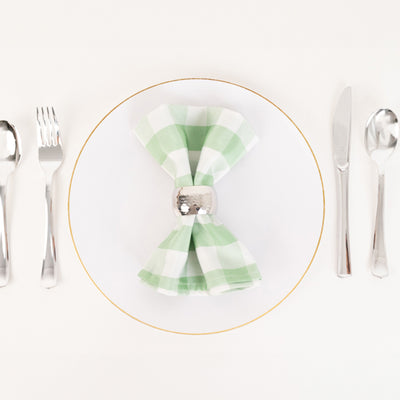Green checkered napkin on a white plate with silver cutlery arrangement.