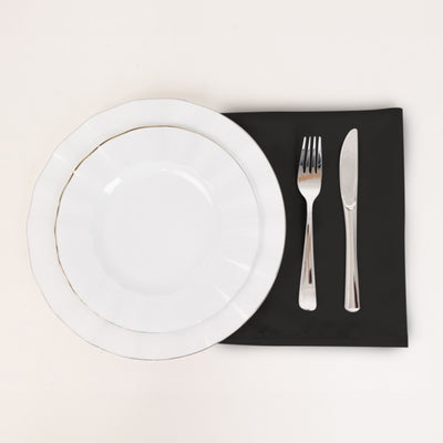 Elegant white dinnerware set with silver accents on a black napkin.