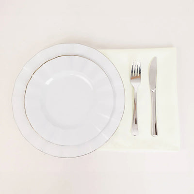 Elegant white dinnerware set with fork and knife on a soft cloth.
