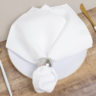 Elegant white napkin with silver napkin ring on a plate.