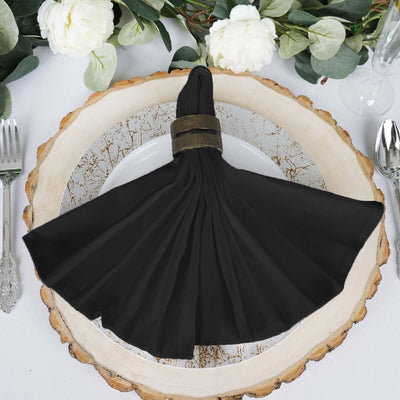 Black pleated napkin on a rustic wooden plate with greenery