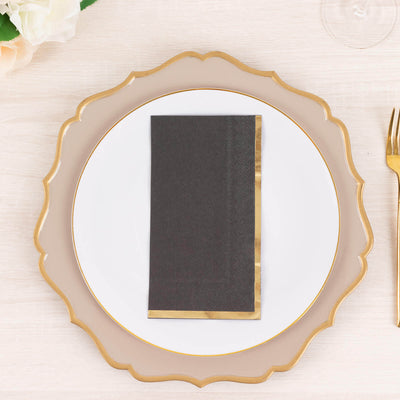 Elegant black napkin with gold trim on a decorative plate.