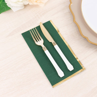 Gold fork and knife on a green napkin with gold trim, styled for dining.