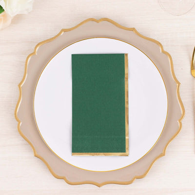 Green napkin with gold trim on an elegant white plate.