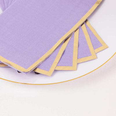 Purple napkins with gold trim on a white plate.