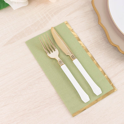 Gold cutlery set on a green napkin with a gold trim.