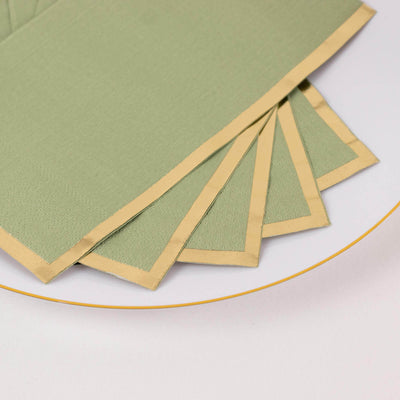 Green napkins with gold trim arranged on a plate.