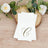 Elegant white napkins with gold monogram "C" on rustic wood background.