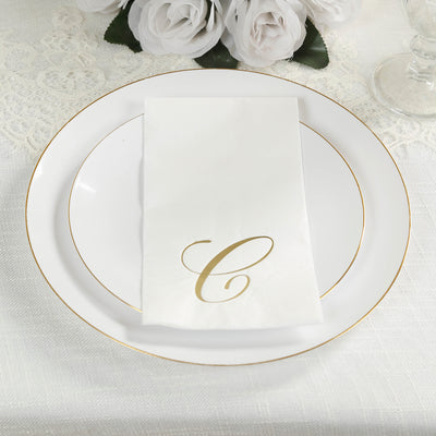 Elegant white plate with gold rim and folded napkin featuring a gold letter "C".