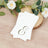 Elegant monogrammed napkins on a rustic wooden slice with floral accents.