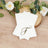 Elegant white napkins with gold monogram "F" on a wooden surface.