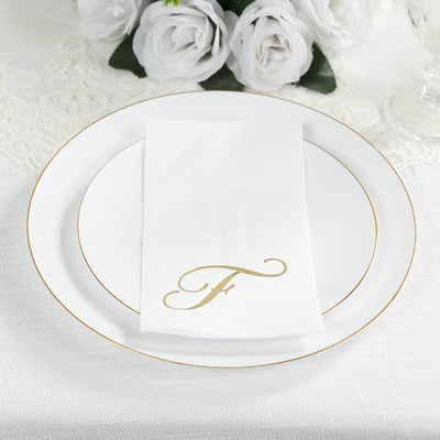 Elegant white plate with gold trim and personalized napkin on a textured tablecloth.