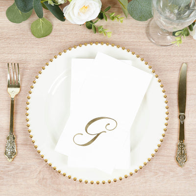 Elegant white dinner napkin with gold initial "G" on a decorative plate.