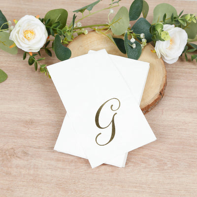 Elegant white napkins with a gold monogram 'G' design.
