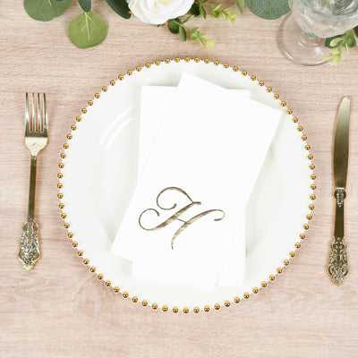 Elegant white dinner plate with gold beaded rim and monogrammed napkin.