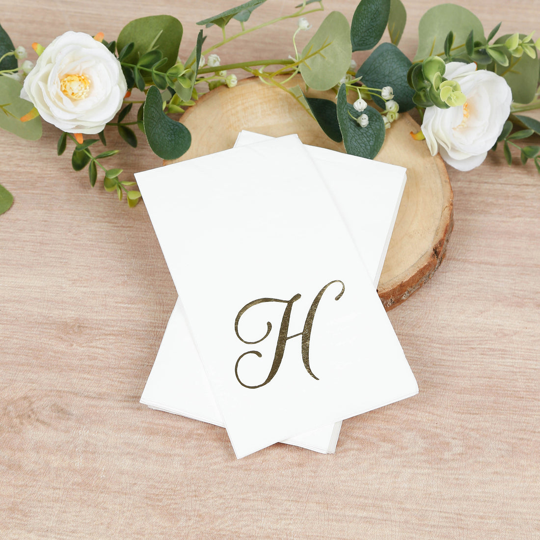 Elegant monogrammed stationery with a gold letter 'H' on a wooden surface.