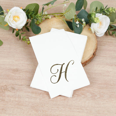 Elegant monogrammed stationery with a gold letter 'H' on a wooden surface.