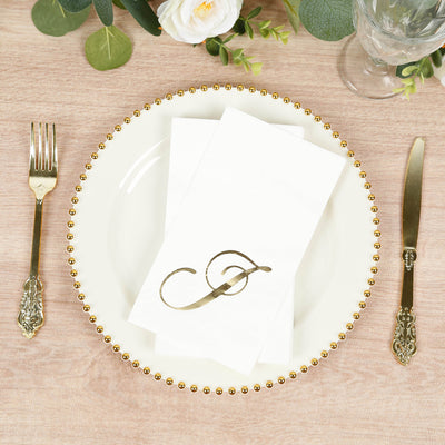Elegant gold monogram napkin on a decorative plate with silverware.
