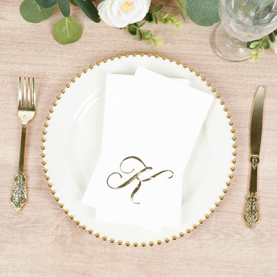 Elegant white dinner plate with gold beaded rim and folded napkin featuring a monogram "K".
