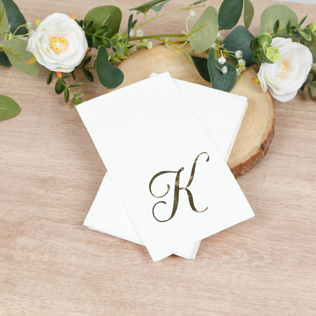 Elegant monogrammed notecards with a gold "K" design on a wooden surface.