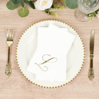 Elegant dinner plate with gold beaded rim and monogrammed napkin on wooden table.