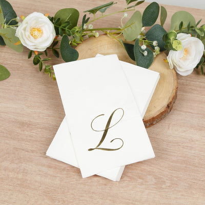 White napkins with elegant gold "L" monogram on a wooden surface.