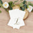 White napkins with elegant gold "L" monogram on a wooden surface.
