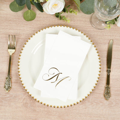 Elegant white napkin with gold monogram on decorative plate setting.