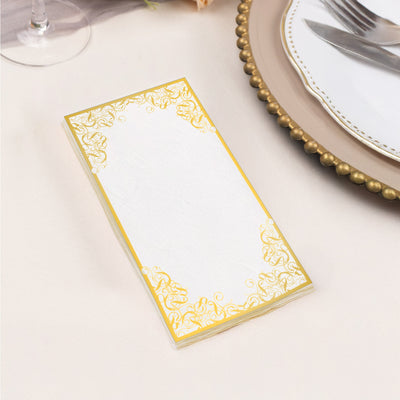 Elegant blank invitation card with gold floral border on a table setting.