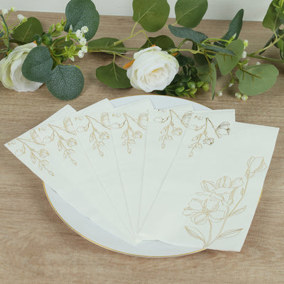 Decorative floral napkins arranged on a plate with greenery and flowers in the background.
