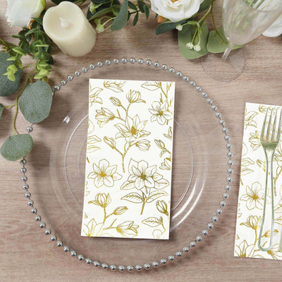 Floral patterned napkin on a clear plate with decorative beads on a wooden table.