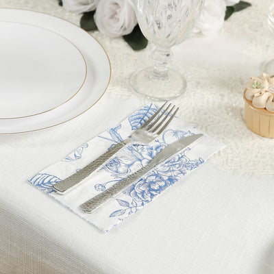 Elegant blue floral napkin with silver cutlery on a table setting.