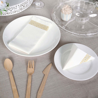 Elegant white dinnerware set with gold-accented napkin and wooden utensils.