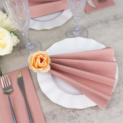 Elegant pink napkin folded with a flower, set on a white plate for dining.