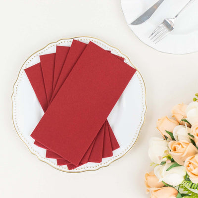 Red paper napkins folded neatly on a decorative plate with flowers in the background.