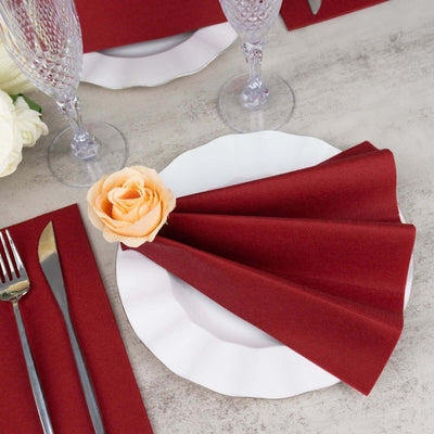 Elegant burgundy napkin elegantly folded on a white plate with a rose.