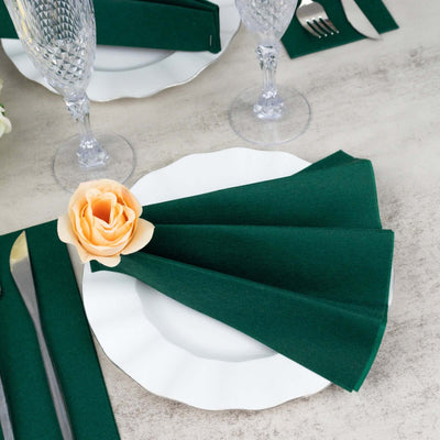 Elegant green napkin and rose on a white plate, set for dining.