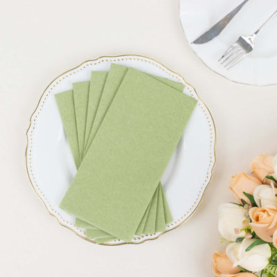 Green paper napkins stacked on a decorative plate with a floral arrangement.