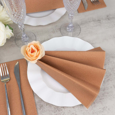 Elegant table setting with folded brown napkin and rose on white plate.