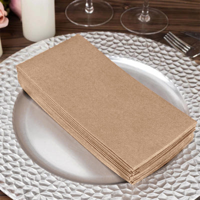 Brown paper napkins stacked on a silver charger plate at a dining table