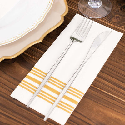 Elegant silver cutlery on a striped linen napkin with decorative plates.