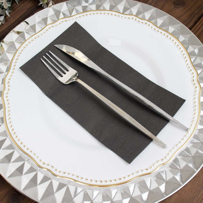 Elegant silver fork and knife on a black napkin atop a decorative plate.