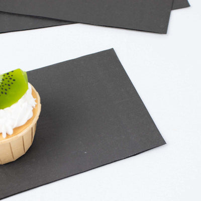 Cupcake with cream and kiwi slice on black paper background.