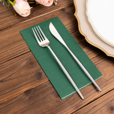 Green table setting with fork and knife on a wooden surface.