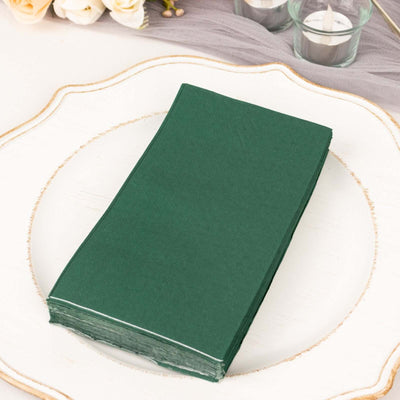 Green paper napkins stacked on a decorative plate.