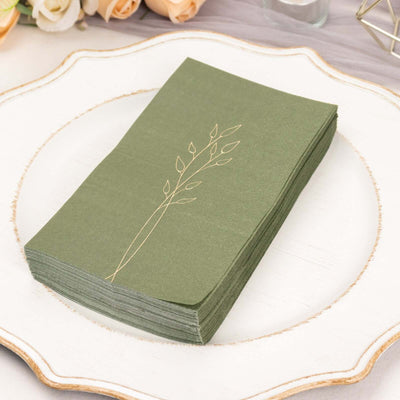Green napkins with gold leaf design on a decorative plate.