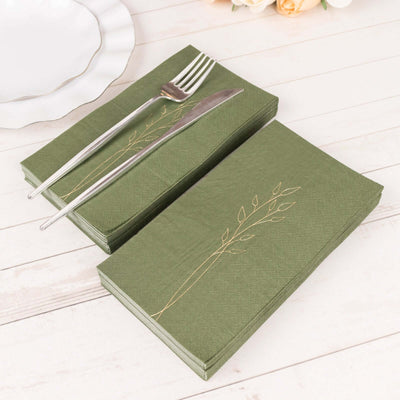 Green napkins with gold leaf design, arranged with cutlery on a wooden surface.