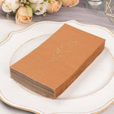 Elegant brown napkins with gold leaf design on a decorative plate.
